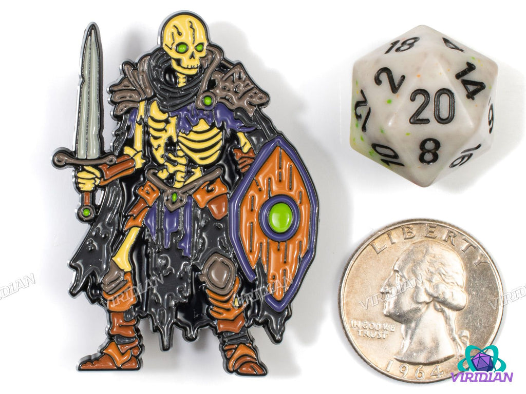 Size comparison of Pin Pals: Skeleton Warrior enamel pin next to a D20 die and US quarter, highlighting its fantasy-themed detail.